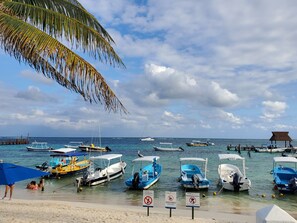 Una playa con barcos amarrados y una estructura de techo de paja.