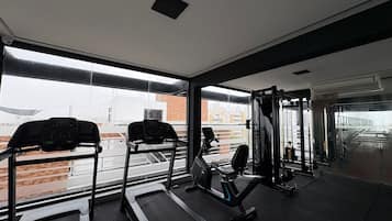 Een fitnessruimte met loopbanden, een hometrainer en krachtapparaten.