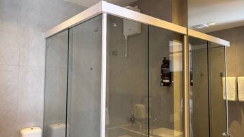 Un baño moderno con ducha envuelta en vidrio, un secador de manos y un perchero para toallas.