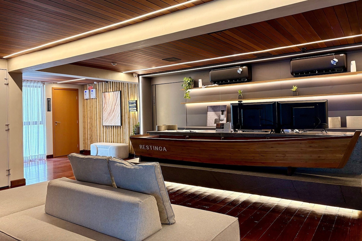 A modern reception area with a wooden reception desk, a seating area with a sofa, and a large mirror reflecting the space.