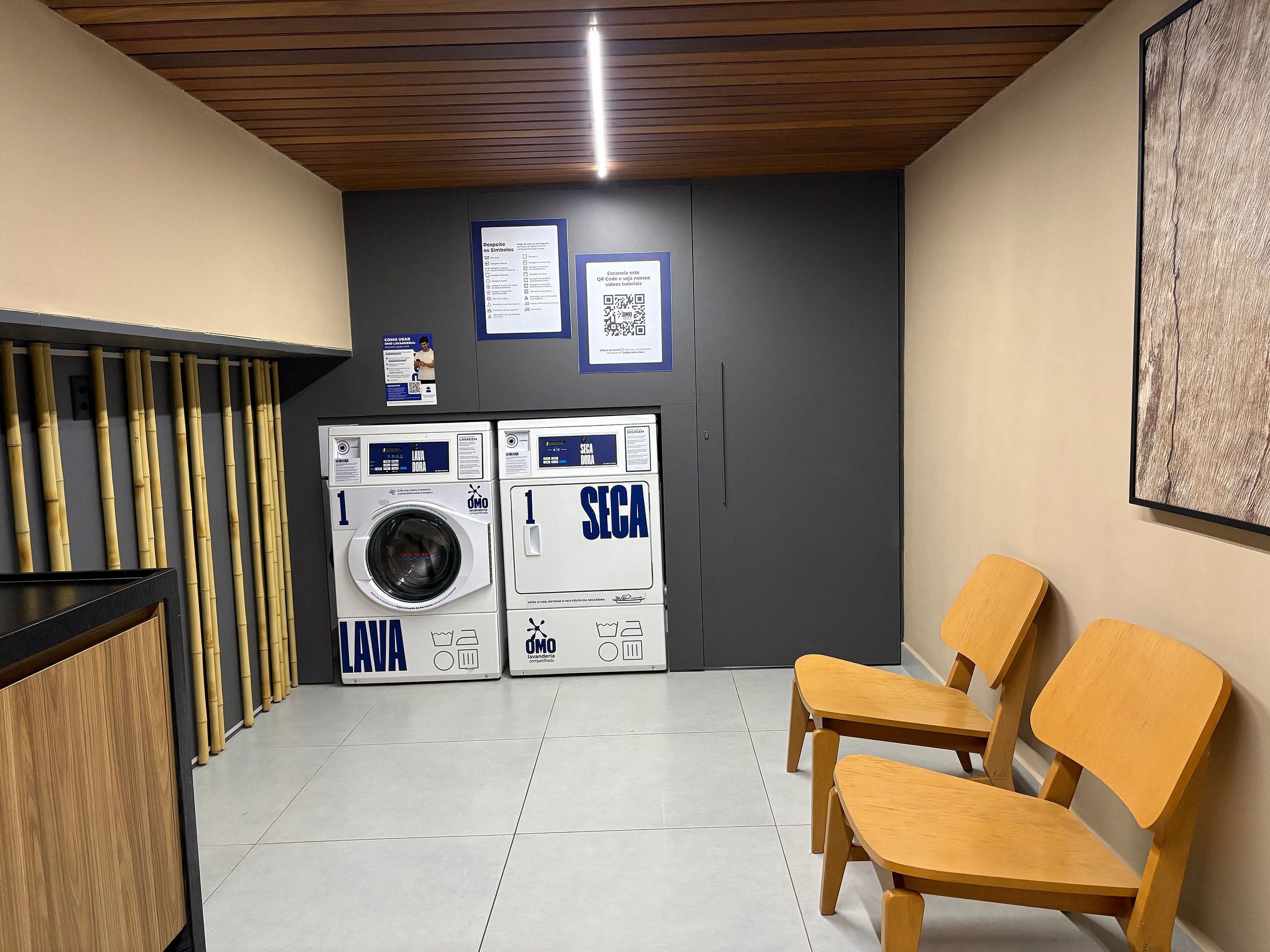 Un área de lavandería con dos lavadoras, un banco de madera y un código QR en la pared.