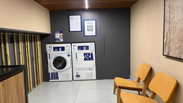 Un área de lavandería con dos lavadoras, un banco de madera y un código QR en la pared.