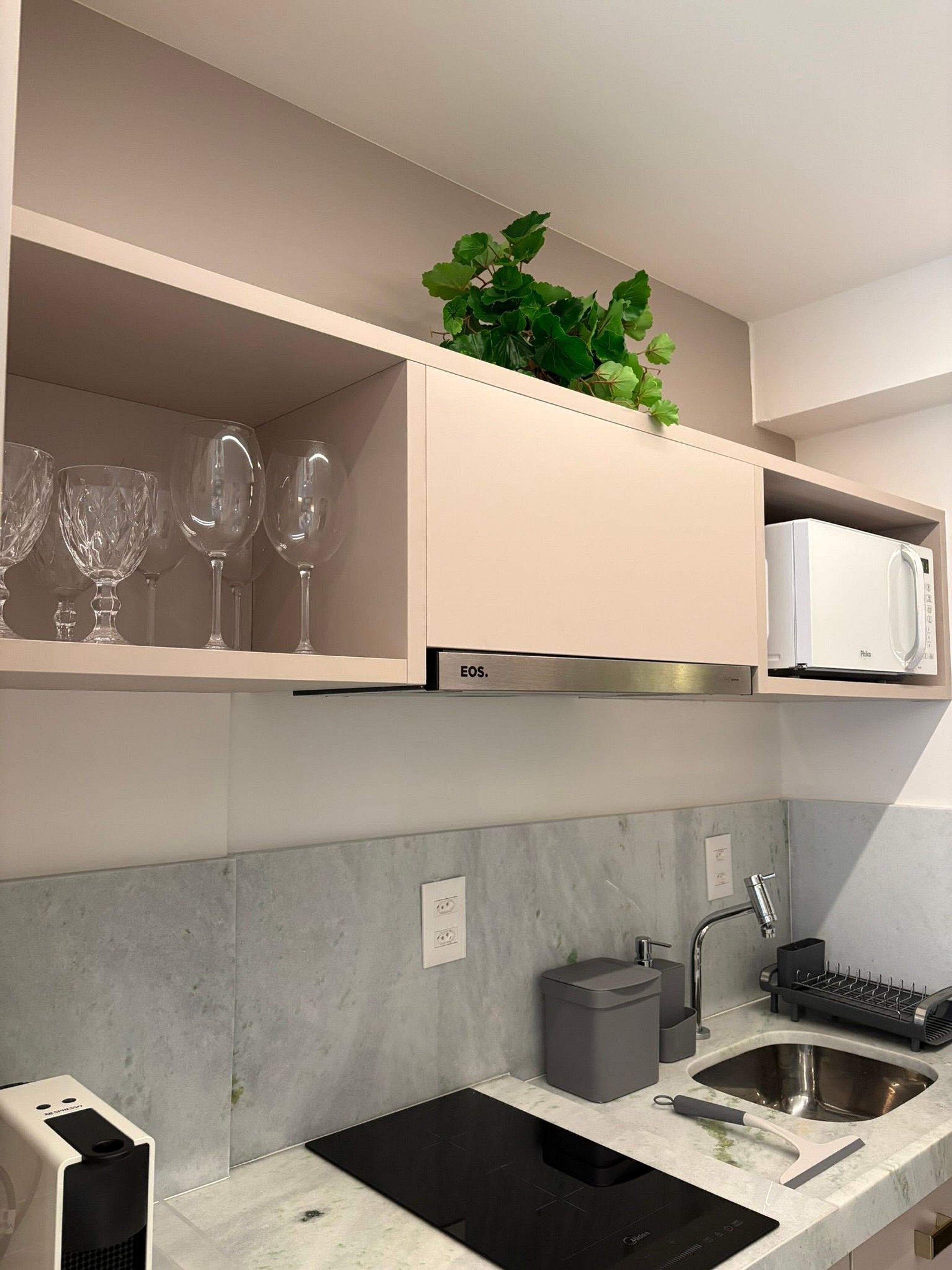 A modern kitchen with a built-in microwave, a sink with a faucet, and a countertop with a black induction cooktop.