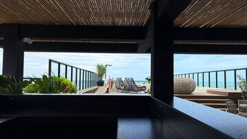Un interior moderno con vista al océano, que presenta un techo de madera, una zona de estar con una mesa redonda y una planta en maceta.