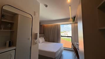 Ein Hotelzimmer mit Bett, Schreibtisch, Stuhl, kleinem Tisch und einem Fenster mit Vorhängen.
