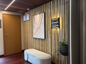 A reception area with a wooden door, a wall-mounted sign, a framed artwork, and a bench. - Refugio Sofisticado no Restinga (João Pessoa)