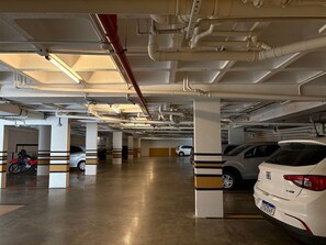 A multi-level parking garage with concrete pillars and overhead pipes. - Refugio Sofisticado no Restinga (João Pessoa)