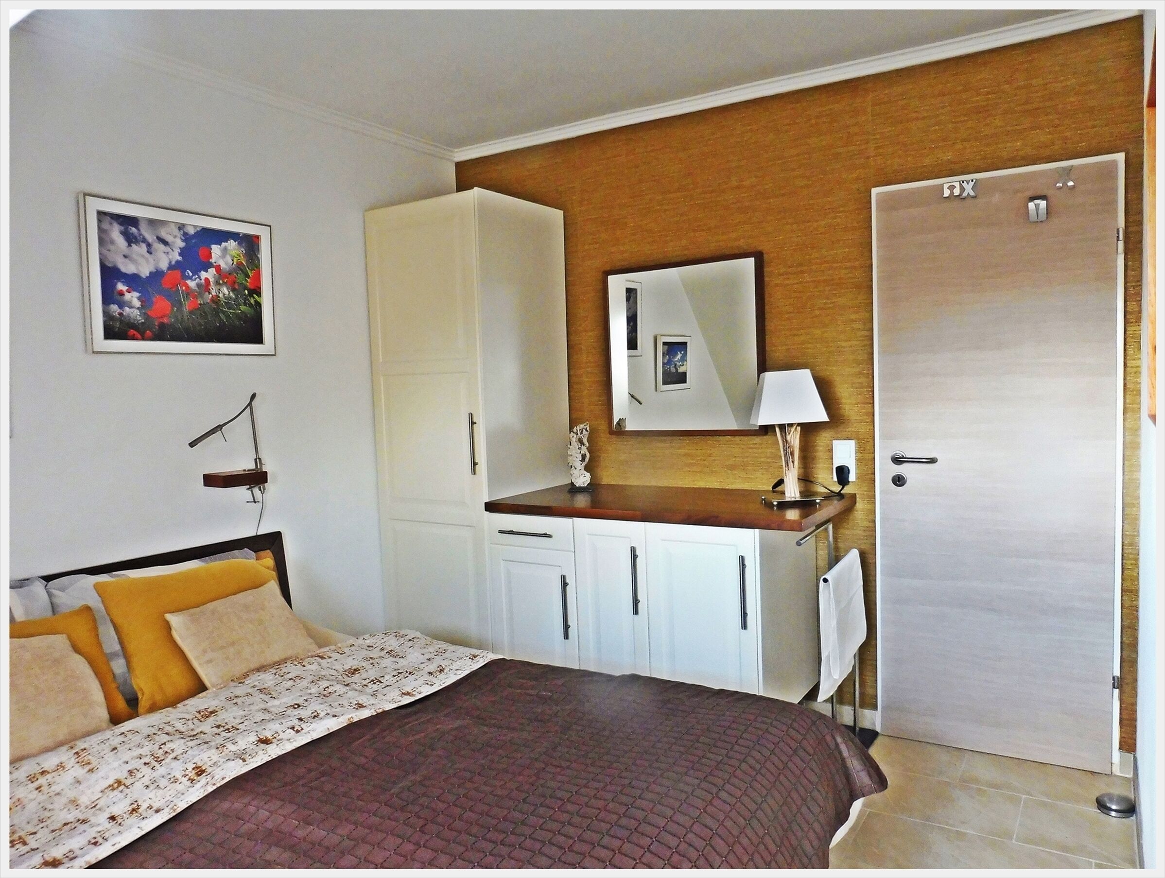 Une chambre à coucher avec un lit, une armoire, un miroir et une porte.