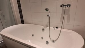 Una bañera blanca independiente con cabezal de ducha manual y grifo integrado.