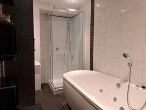 Ein modernes Badezimmer mit einer freistehenden Badewanne, einer gläsernen Dusche und einem dunklen Holzschrank.