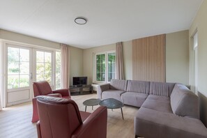 Ein Wohnzimmer mit einer Couch, Sesseln, einem Couchtisch und einem Fernseher.