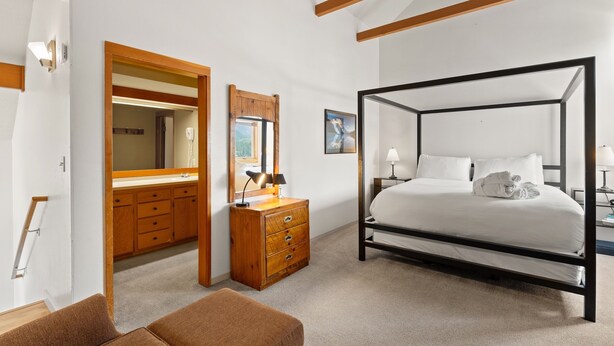 Une chambre à coucher avec un lit à baldaquin, une commode en bois, un miroir et une table de chevet avec une lampe.