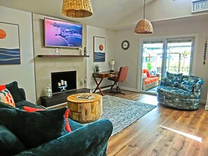 A living room with a fireplace, a television, and a seating area with a sofa and a chair. - Just Us River Retreat (Weeki Wachee)