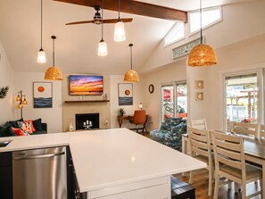 A modern kitchen with a large island, pendant lighting, and a dining area with wooden chairs. - Just Us River Retreat (Weeki Wachee)