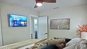 Ett sovrum med en säng, en tv som är monterad på väggen och en dörr som leder till ett annat rum.