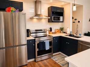 A modern kitchen with stainless steel appliances, dark cabinetry, and a microwave above the counter. - Just Us River Retreat (Weeki Wachee)