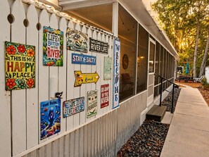 A building with a white exterior and a series of colorful signs on the wall. - Just Us River Retreat (Weeki Wachee)