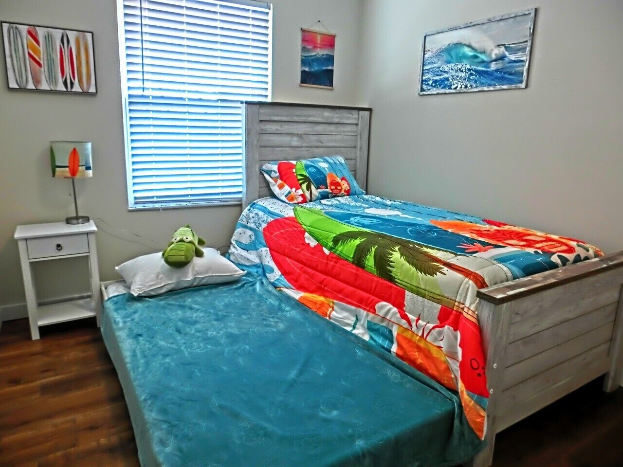 A bedroom with a bed, a nightstand, a wall clock, and a window with blinds.