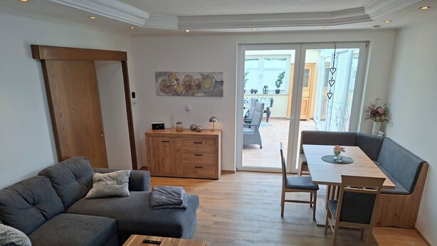 A modern living room with a sofa, coffee table, and a dining area with a bench and table. - A hidden gem in the Emsland region: the "Ferienglück" vacation rental—spacious, ground-floor, bright, and idyllic. (Meppen)