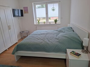 A bedroom with a bed, bedside table, lamp, and a window with blinds.