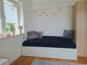 A bedroom with a bed, a window with blinds, a bedside table with a lamp, and a wall-mounted decoration. - A hidden gem in the Emsland region: the "Ferienglück" vacation rental—spacious, ground-floor, bright, and idyllic. (Meppen)