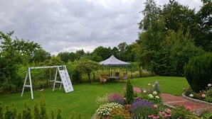 A garden with a swing set, a gazebo, and a variety of flowers. - A hidden gem in the Emsland region: the "Ferienglück" vacation rental—spacious, ground-floor, bright, and idyllic. (Meppen)