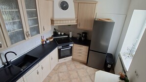 A kitchen with a black countertop, a stainless steel refrigerator, and a clock on the wall. - A hidden gem in the Emsland region: the "Ferienglück" vacation rental—spacious, ground-floor, bright, and idyllic. (Meppen)