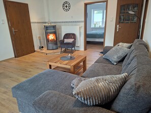 A cozy living room with a fireplace, a sofa, a chair, and a wooden coffee table.