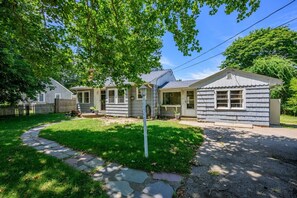 Ein zweistöckiges Haus mit Veranda, kleiner Garage und gepflegtem Rasen.
