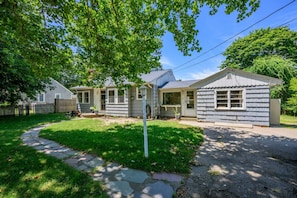 A two-story house with a front porch, a small attached garage, and a well-maintained lawn. - Recently Renovated, Centrally Located Yarmouth Cottage (Yarmouth)