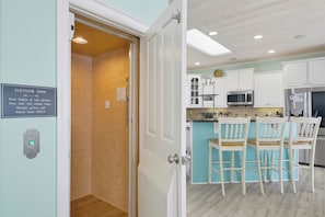 A kitchen with white cabinets, a microwave, and a refrigerator. - Oceanfront with hot tub and elevator (North Topsail Beach)