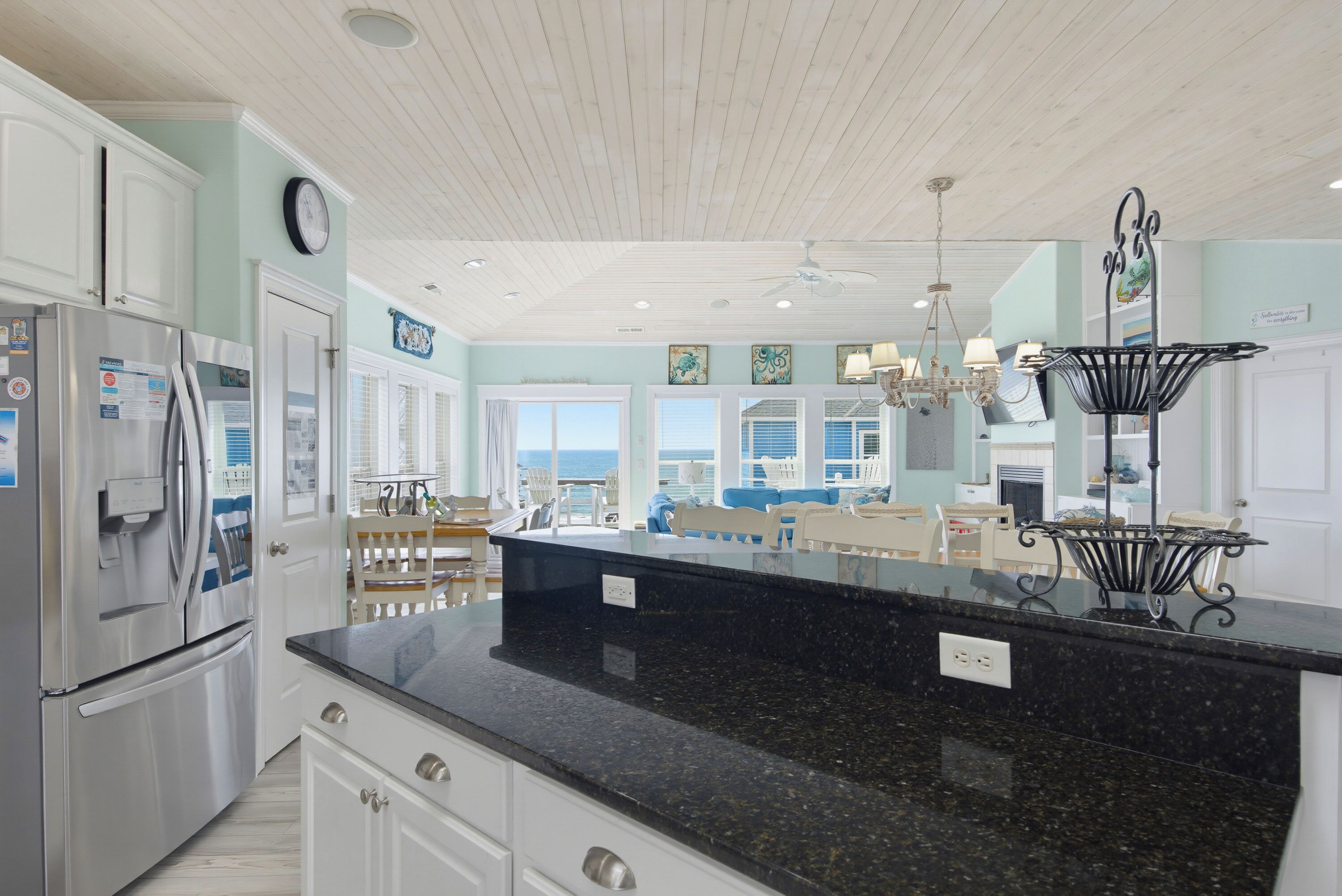A kitchen with a large island, white cabinetry, and a view to the outside.