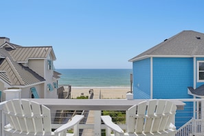 A beach view from a balcony with white chairs and a wooden deck. - Oceanfront with hot tub and elevator (North Topsail Beach)