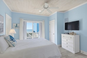 A bedroom with a bed, a dresser, a television, and a view of the ocean through a window. - Oceanfront with hot tub and elevator (North Topsail Beach)