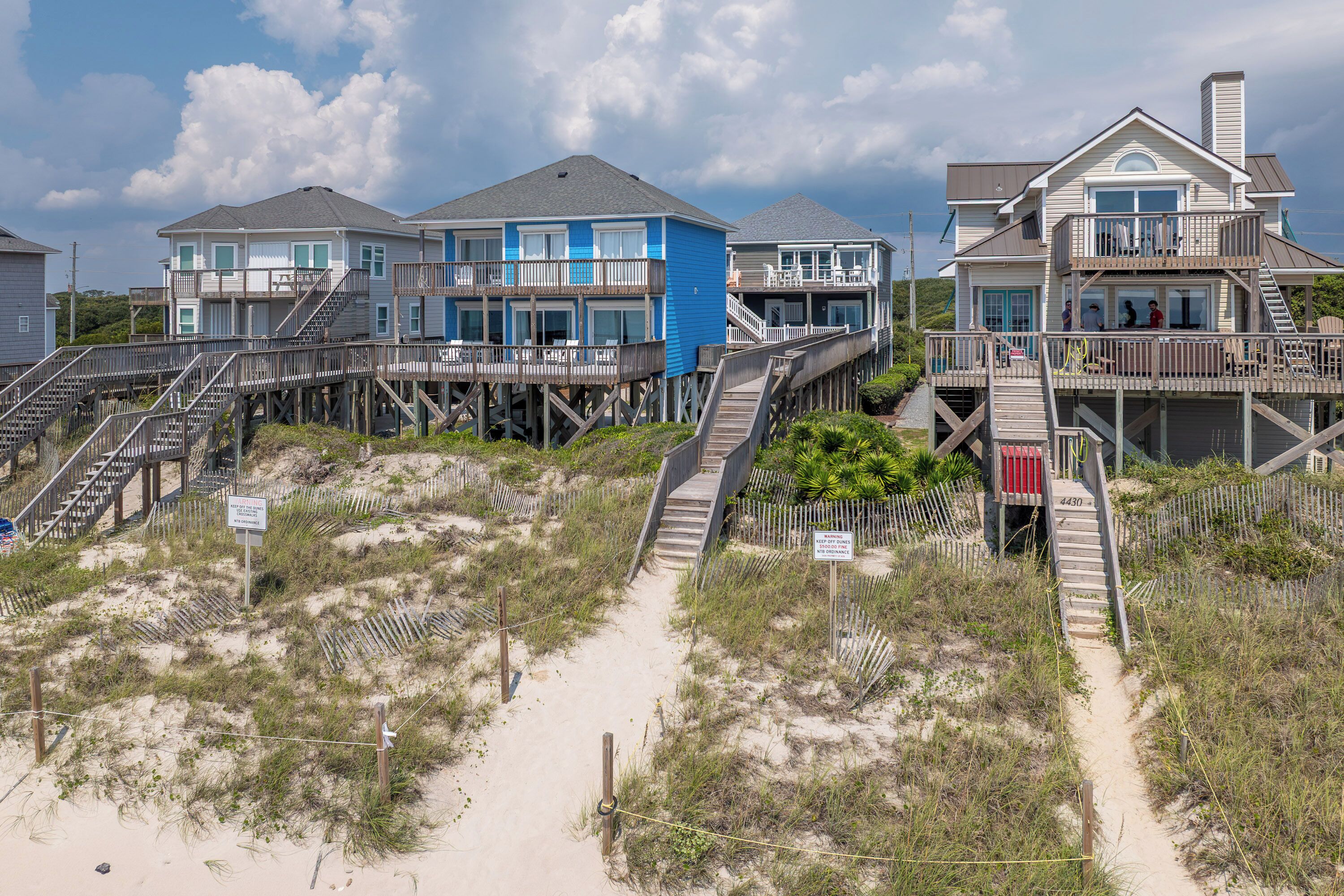 Une propriété située en bord de mer, comprenant plusieurs maisons reliées par des passerelles en bois.