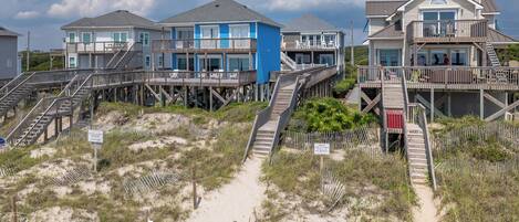 Une propriété située en bord de mer, comprenant plusieurs maisons reliées par des passerelles en bois.