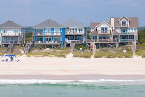 A beachfront property with multiple houses, each featuring a balcony and a view of the ocean. - Oceanfront with hot tub and elevator (North Topsail Beach)