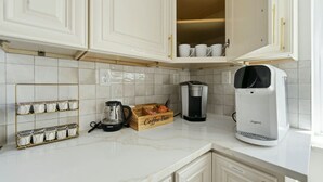 A kitchen with white cabinets, a coffee maker, a coffee grinder, and a mug rack. - Modern West End Home | BeltLine/Downtown Access (Atlanta)