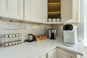 A kitchen with white cabinets, a coffee maker, a coffee grinder, and a mug rack. - Modern West End Home | BeltLine/Downtown Access (Atlanta)