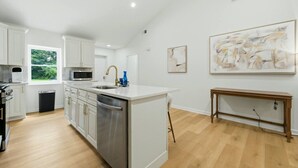 A modern kitchen with white cabinetry, stainless steel appliances, and a large island. - Modern West End Home | BeltLine/Downtown Access (Atlanta)