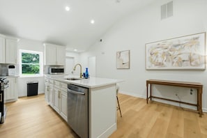 A modern kitchen with white cabinetry, stainless steel appliances, and a large island. - Modern West End Home | BeltLine/Downtown Access (Atlanta)