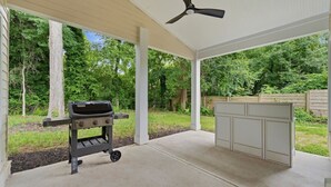 An outdoor patio with a grill and a built-in bar area, surrounded by trees. - Modern West End Home | BeltLine/Downtown Access (Atlanta)