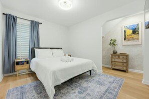 A bedroom with a bed, a nightstand, a dresser, a window with curtains, and a wall-mounted painting. - West End Gem | Near Mercedes-Benz Stadium, Pet OK (Atlanta)