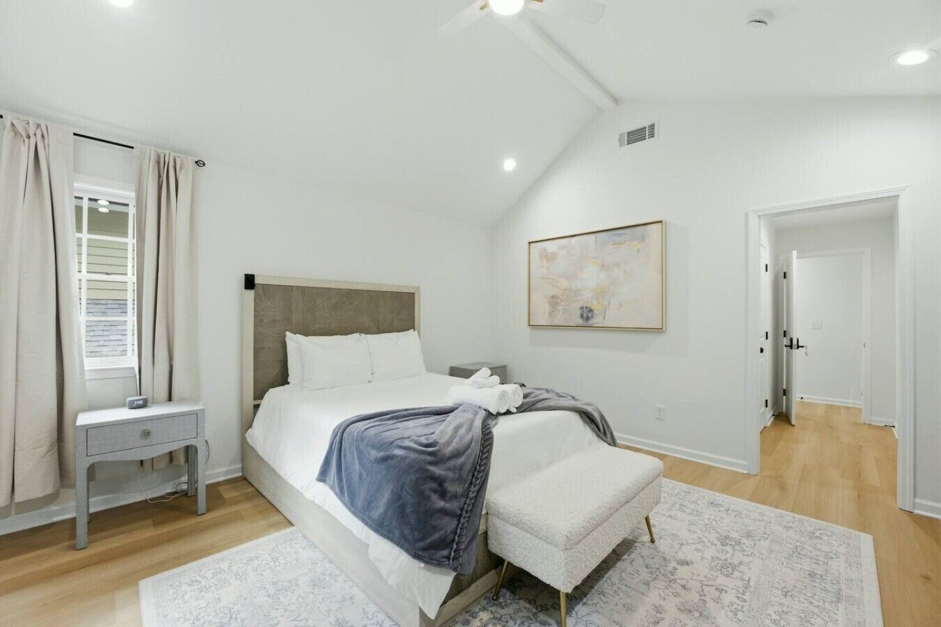 Un dormitorio con cama, mesita de noche y un cuadro en la pared.