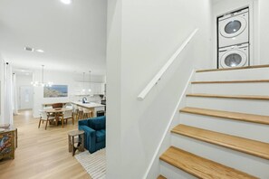 Ein modernes Interieur mit einer Treppe, einer Küche mit weißen Schränken und einem Essbereich mit einem blauen Sofa.