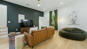 Una sala de estar moderna con un sofá, un sillón de peluche, un televisor y un cuadro en la pared.