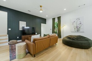 A modern living room with a sofa, a bean bag, a television, and a painting on the wall. - Atlanta West End Getaway | Near BeltLine/Downtown (Atlanta)
