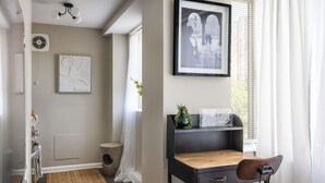 A room with a desk, chair, framed artwork, and a window with curtains. - Gracious 2 Bed 2 Bath Apartment with Free Parking (Arlington)