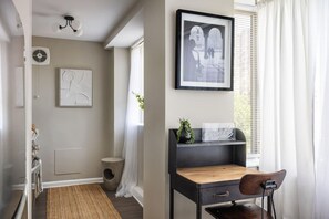 A room with a desk, chair, framed artwork, and a window with curtains. - Gracious 2 Bed 2 Bath Apartment with Free Parking (Arlington)