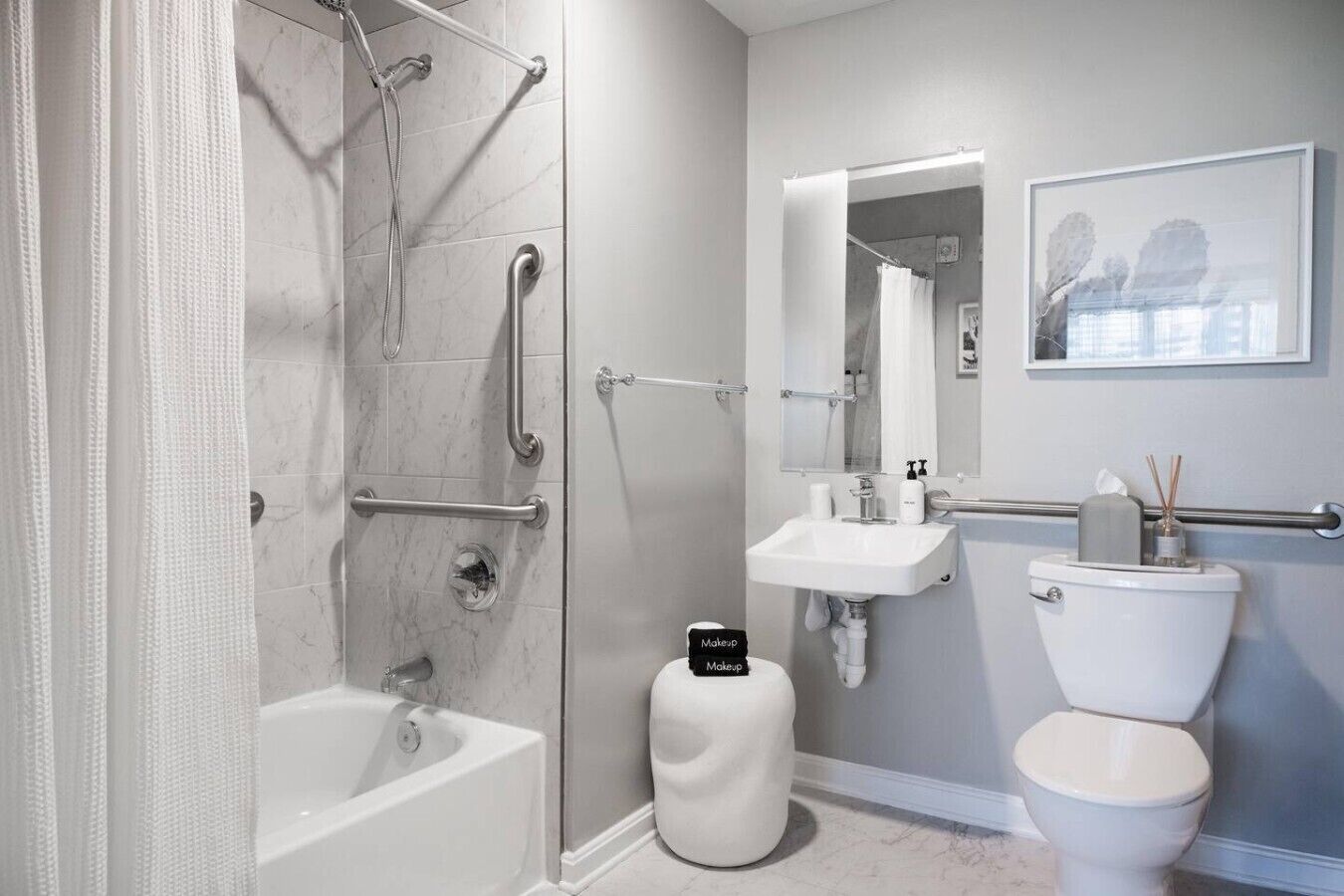 A modern bathroom with a walk-in shower, grab bars, a vanity with a mirror, and a toilet.
